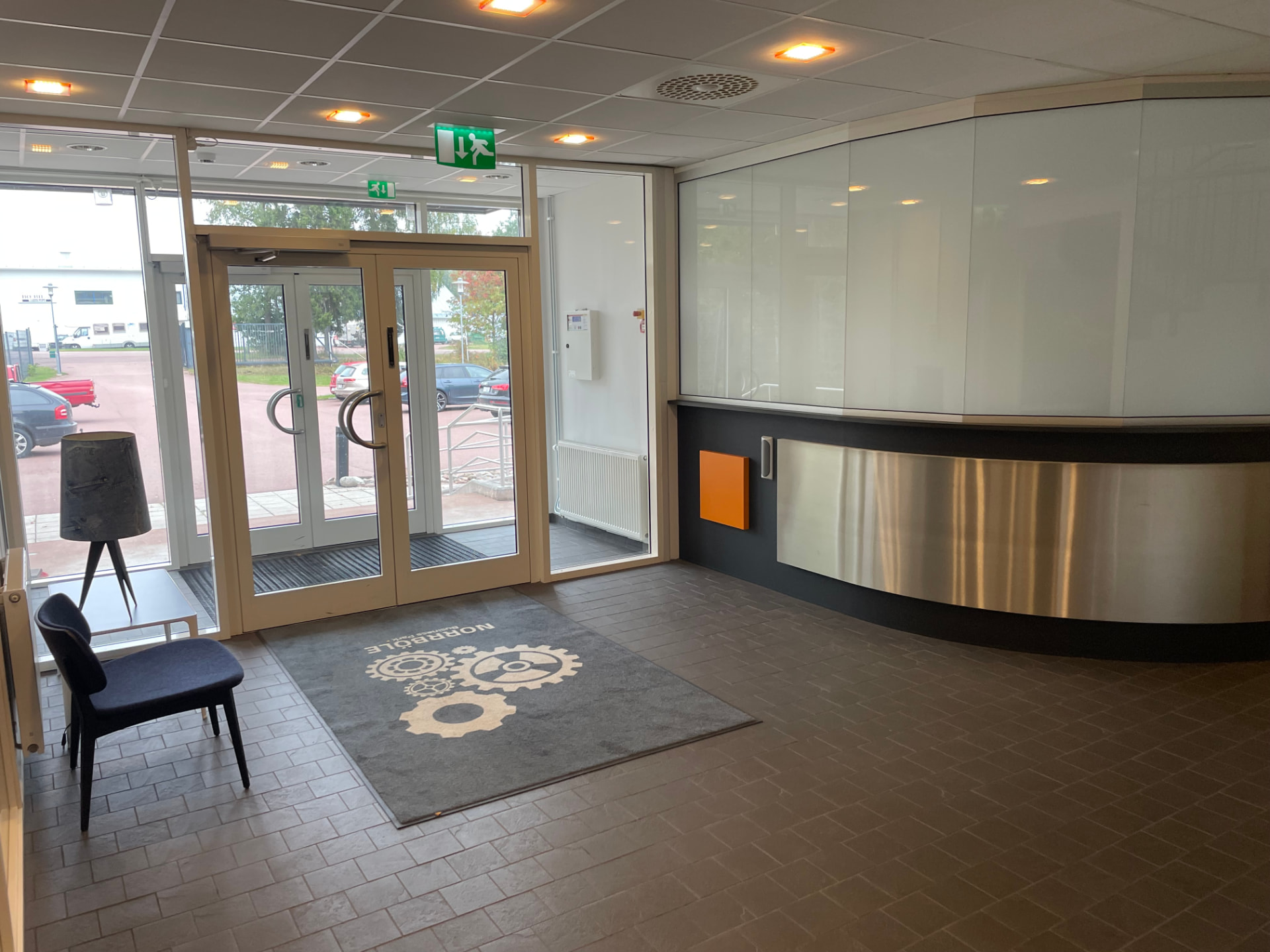 Entré med glaspartier, receptiondisk i borstad metall och Norrböle Business Park-logotyp i golvmattan