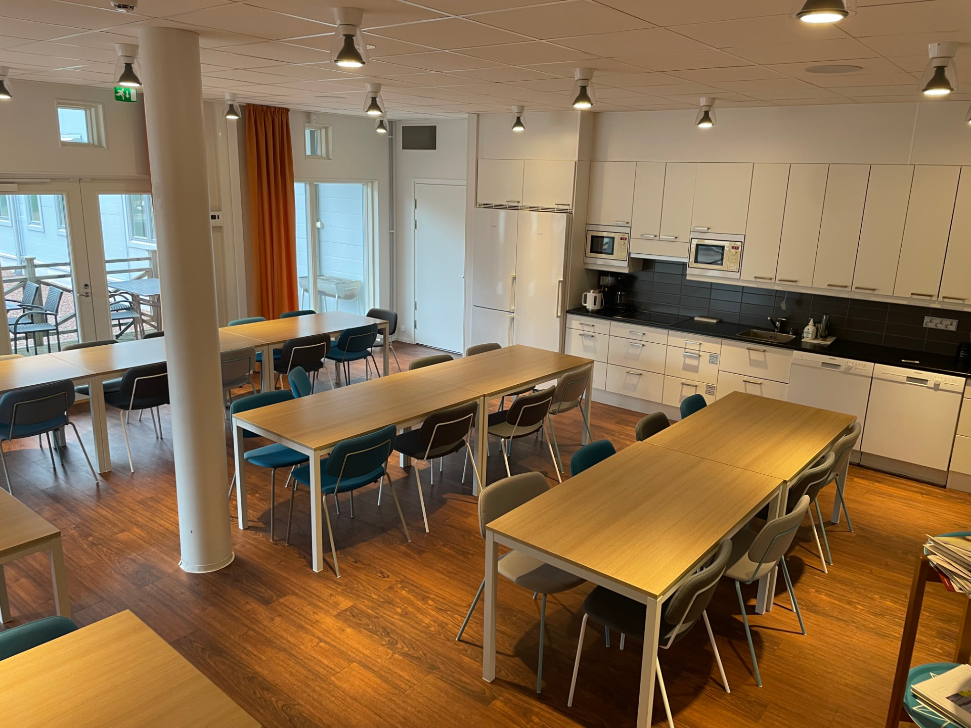 Gemensam matsal med köksavdelning, bord och stolar samt utgång till terrassen